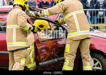 Firecrew de l'Irlande du Nord Service d'incendie et de sauvetage de démontrer comment utiliser l'équipement de coupe hydraulique pour libérer un conducteur qui était coincé dans une voiture après un Banque D'Images