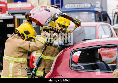 Firecrew de l'Irlande du Nord Service d'incendie et de sauvetage de démontrer comment utiliser l'équipement de coupe hydraulique pour libérer un conducteur qui était coincé dans une voiture après un Banque D'Images