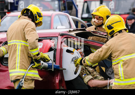 Firecrew de l'Irlande du Nord Service d'incendie et de sauvetage de démontrer comment utiliser l'équipement de coupe hydraulique pour libérer un conducteur qui était coincé dans une voiture après un Banque D'Images