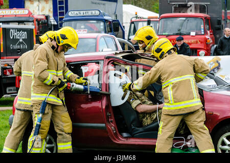 Firecrew de l'Irlande du Nord Service d'incendie et de sauvetage de démontrer comment utiliser l'équipement de coupe hydraulique pour libérer un conducteur qui était coincé dans une voiture après un Banque D'Images