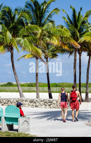 Miami Beach Florida,Ocean Drive,Lummus Park,cococotiers palmiers,arbres,mur de corail,Serpentine Way,banc,adultes homme hommes, femme femmes femmes Banque D'Images