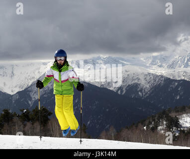 Jeune skieur sautant avec bâtons de ski sur les montagnes et soleil nuageux ciel gris. Montagnes du Caucase. Hatsvali Svaneti, région de la Géorgie. Banque D'Images