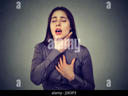 Jeune femme ayant d'asthme ou de suffocation ne peut pas souffle souffrant de problèmes de respiration isolé sur fond gris Banque D'Images