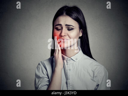 Femme avec couronne de dents sensibles souffrant de douleur problème touchant l'extérieur de la bouche à part isolé sur fond gris. L'émotion négative Banque D'Images