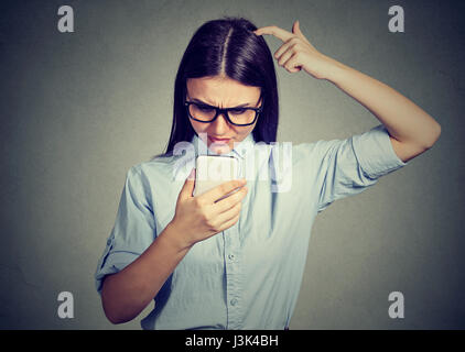 Clueless dumb girl à avoir des problèmes avec son smartphone. Technologie concept compliqué Banque D'Images