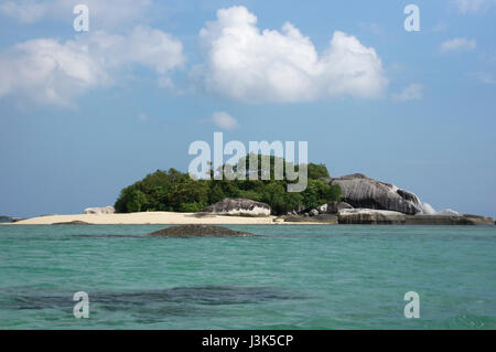 Petite île avec plage de sable blanc et de granit naturel rock formation et la végétation verte entourée par l'eau de l'océan bleu vert dans l'après-midi, Beli Banque D'Images