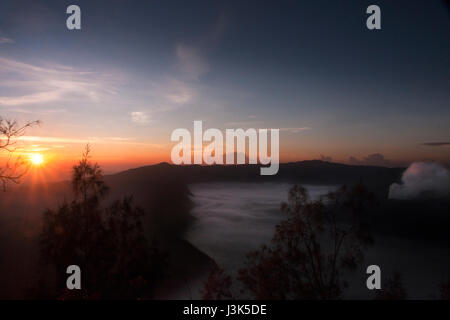 Mist planant vers le volcan Bromo orange le matin pendant le lever du soleil, à l'Tengger Semeru National Park dans l'Est de Java, Indonésie. Banque D'Images