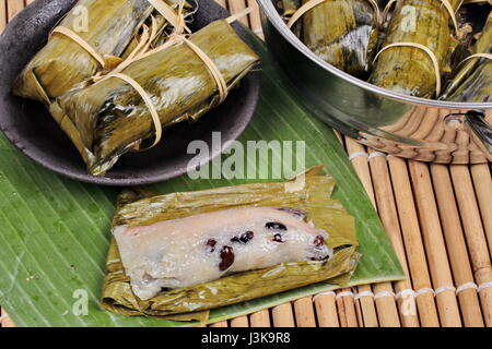 Thai populaire dessert, le riz gluant en streaming et black bean dans la feuille de banane appel Khao Tom Mad in Thai servi sur plat avec cuit en pot. Banque D'Images