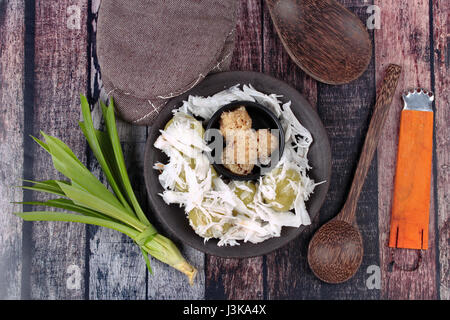 Dessert thaïlandais à la vapeur, enveloppement de la farine de coco purée de patates douces recouvertes par appel de coco Khanom Tom en thaï servi dans la plaque noire avec feuilles de pandan et ki Banque D'Images