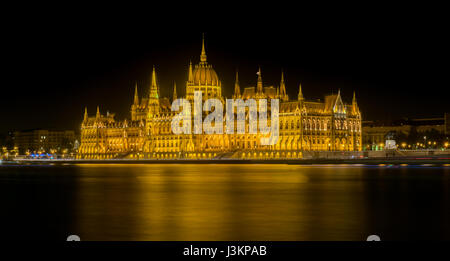 Vue nocturne de l'édifice du parlement hongrois situé sur le côté Pest du Danube à Budapest, avec des sentiers de lumière à partir de bateaux de passage v Banque D'Images