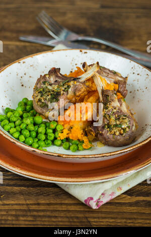 Côtelettes d'agneau au romarin le dîner à la carotte et le panais en purée et petits pois Banque D'Images