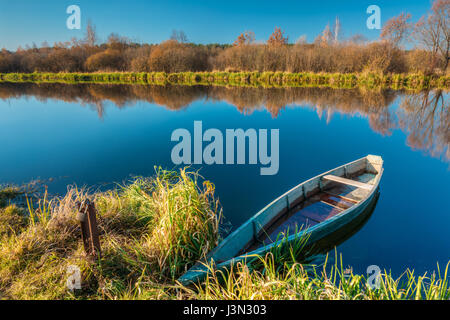 La pittoresque rivière Paysage Automne Automne jaunies, banque du fleuve avec un petit bleu en bois attachés de barques de pêche sur l'eau immobile Skippet Banque D'Images