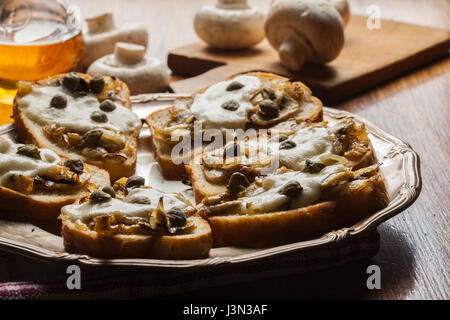 Crostini avec poêlée de champignons, l'oignon et de fromage mozzarella sur une plaque Banque D'Images