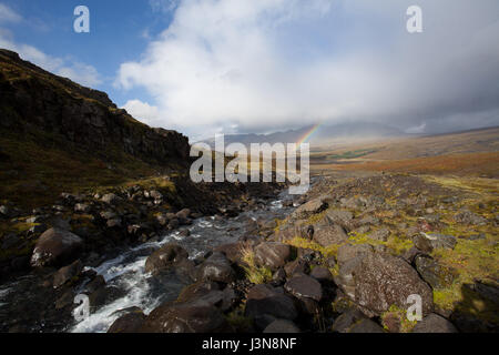 Bel arc-en-ciel dans la vallée entre les montagnes. Petit ruisseau d'une cascade. Randonneur est descendant. Banque D'Images