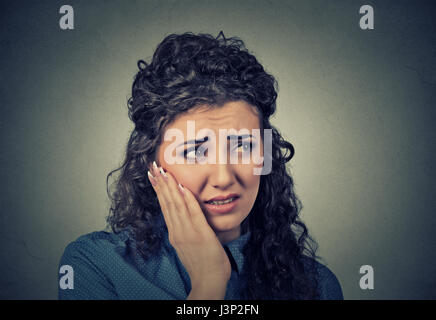 Closeup portrait jeune femme avec couronne de dents sensibles problème sur le point de pleurer de douleur de toucher l'extérieur de la bouche à part isolé sur gray backgroun Banque D'Images