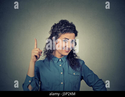 Portrait jeune femme a idée, pointant avec le doigt jusqu'à heureux isolé mur gris. Résoudre un problème concept. Face à l'organe d'expression, Banque D'Images