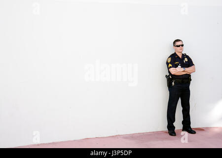 Miami Beach Florida,homme hommes hommes,police,policier,officier,debout,mur blanc,bras croisés,garde,travail,employé travailleurs personnel,uniforme,gu Banque D'Images