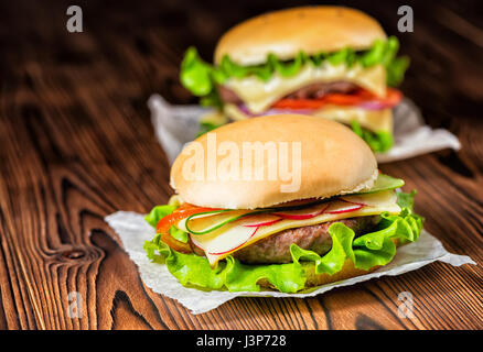 Deux des cheeseburgers complet avec des légumes, des épices et de la viande bovine sur fond de bois foncé, copy space Banque D'Images