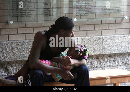 Homme afro-américain avec une petite fille dormant dans les bras Banque D'Images