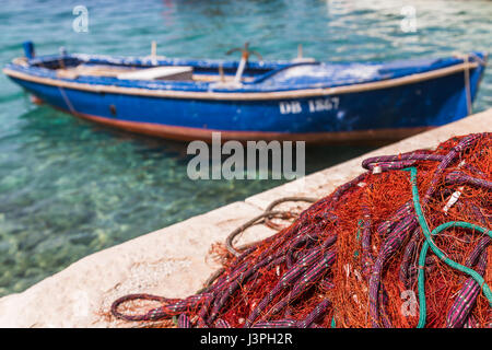 De couleur rouge vif les filets de pêche sécher par un petit bateau sur l'île de Kolocep. Banque D'Images