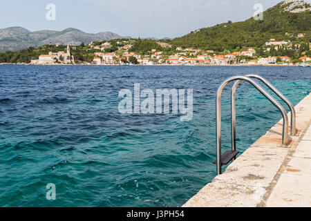 Quelques marches mènent vers le bas du quai sur l'île croate de Lopud et dans les eaux turquoises de la mer Adriatique. Banque D'Images