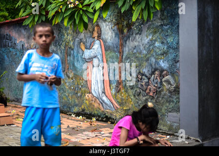 Enfants au premier plan d'une peinture murale représentant Jésus priant dans le Gethsémané avant la crucifixion. Banque D'Images