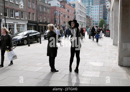 Young women wearing black hat smiling standing avec ami sur Brushfield Street près de Marché de Spitalfields dans East London E1 KATHY DEWITT Banque D'Images