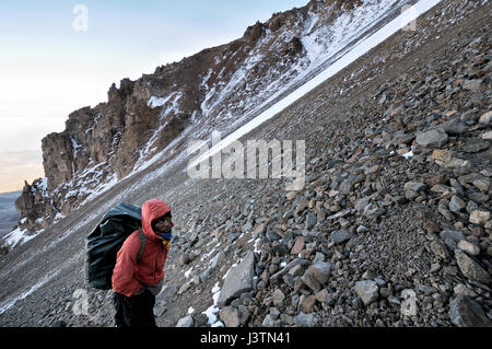 Un portier portant un gros sac à dos, l'ascension de la violation de l'Ouest, le Mont Kilimanjaro National Park, Tanzania Banque D'Images