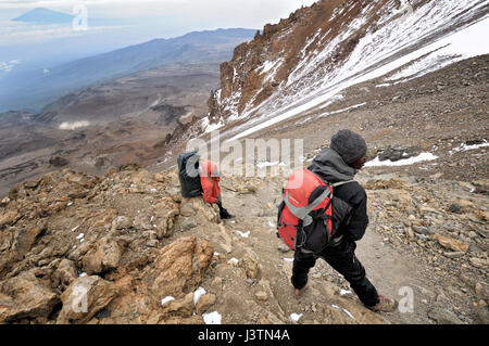 Guide de montagne et porter sur la violation de l'Ouest avec le Mont Meru au loin, le Mont Kilimanjaro National Park, Tanzania Banque D'Images