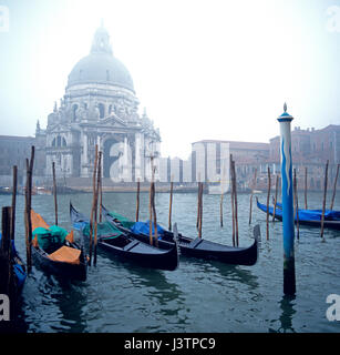 Venise vue de la lagune, à l'église de Santa Maria della saute dans la brume matinale avec Gondoles sur leurs poteaux d'amarrage à l'avant-plan focu Banque D'Images