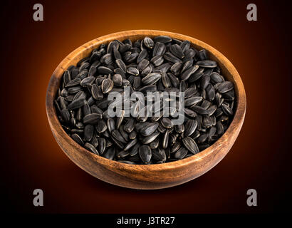Les graines de tournesol noires dans bol en bois isolé Banque D'Images