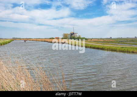 Paysage de polders typiquement hollandais avec moulin et bateau dans le canal Banque D'Images