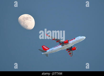 Easyjet Airbus A320 décollant de l'aéroport de Faro avec un trois quart de lune dans le ciel du soir Banque D'Images