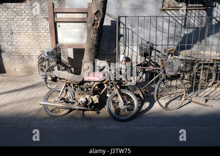 Scène de rue avec les vélos et les motos devant une cour porte dans Beijing Hutong, Chine, le 23 février 2016. Banque D'Images