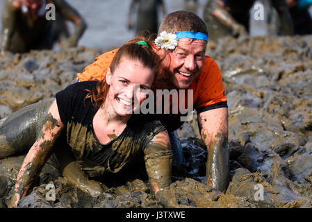 Les concurrents de Mad Maldon Mud Race couverts de boue lors de courses à travers et à travers la rivière Chelmer dans l'Essex, au Royaume-Uni Banque D'Images