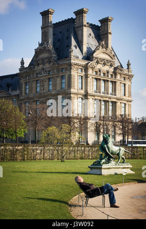 Tourist est reposant sur un banc dans le parc en face du Louvre. Vue depuis l'Avenue du Général Lemonnier au Jardin des Tuileries. Paris. France Banque D'Images