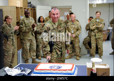 L'AÉRODROME DE BAGRAM, en Afghanistan (28 avril 2017) - L'Adjudant-chef de l'armée américaine John Aloi 4 coupe le cake de félicitations célébrer son dernier vol militaire. Aloi piloté son dernier vol RC-12X Garde-corps aujourd'hui. Son Groupe de travail ODIN/206e bataillon de renseignement militaire coéquipiers sont vus dans l'arrière-plan de célébrer avec lui. Photo de Bob Harrison, les forces américaines en Afghanistan Affaires publiques. Banque D'Images