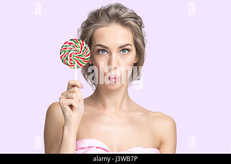 Portrait de funny cute woman with lollipop sur fond rose Banque D'Images