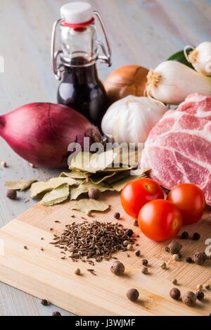 Photo verticale de cumin heap en regard de plusieurs tranches de porc au cou des piquets avec de la graisse. La viande et d'épices est en bambou en bois avec du poivre ou de tomates, o Banque D'Images