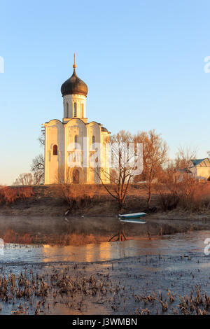 Un lac brumeux avec un bateau en face de l'église au début du printemps à l'aube Banque D'Images