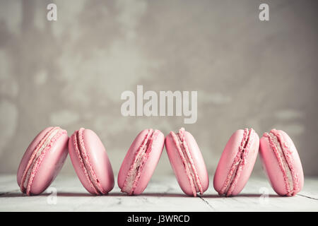 Rangée de macarons Framboise rose pastel ou macarons sur fond noir en béton Banque D'Images