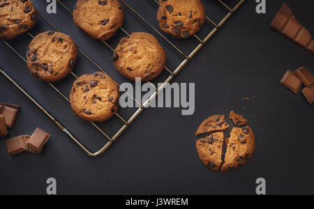 Cookies aux pépites de chocolat sur fond sombre, frais du four en basse lumière Banque D'Images