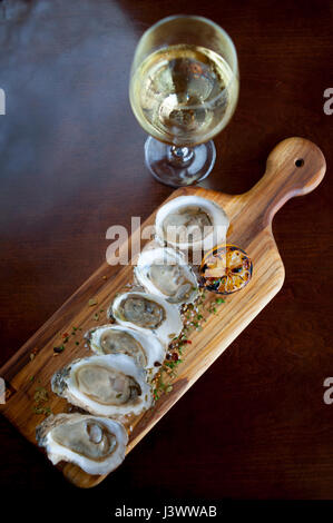 L'alimentation des huîtres crues en demi-coquille avec un verre de vin blanc avec du sel aux herbes saupoudré sur les huîtres Williamsburg Virginia VA Restaurant Waypoint Banque D'Images
