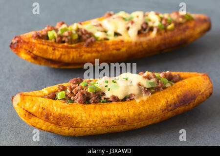 Plantain mûres cuites au four farcies de viande hachée, d'olive, poivron vert et l'oignon, le fromage sur le dessus, parsemer de ciboulette Banque D'Images