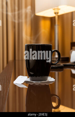 Black tasse de thé chaud sur une table en verre dans une chambre d'hôtel Banque D'Images