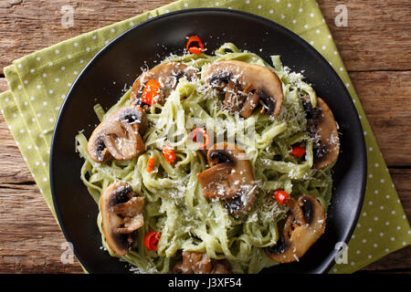 Les pâtes aux épinards poêlée de champignons et parmesan close-up sur une plaque horizontale vue du dessus. Banque D'Images