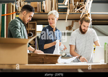 3 jeunes l'emballage produits dans un petit entrepôt Banque D'Images