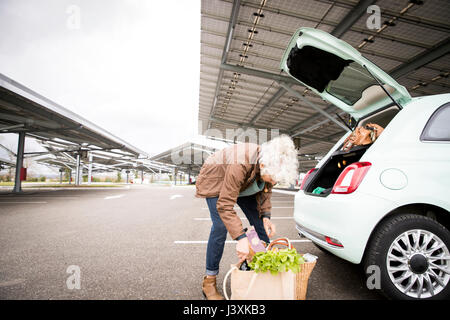 Young woman in car park, le chargement en voiture de démarrage commercial Banque D'Images