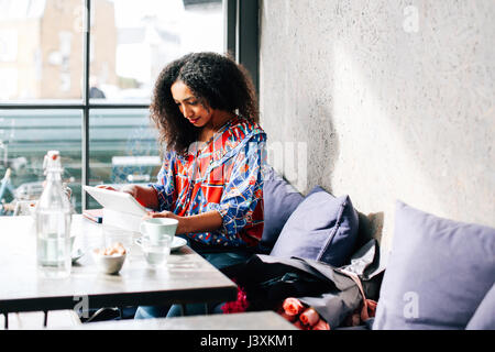 Mid adult woman using digital tablet in cafe Banque D'Images