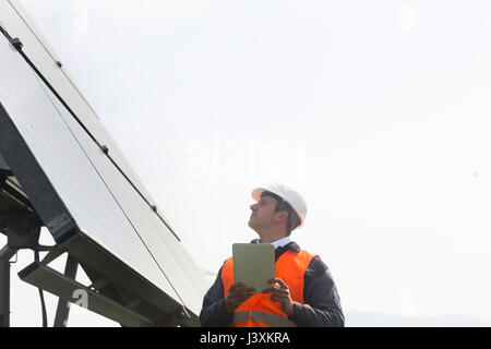 Jeune ingénieur mâle using digital tablet à jusqu'à des panneaux solaires Banque D'Images